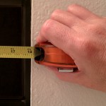 person measurng window opening with tape measure